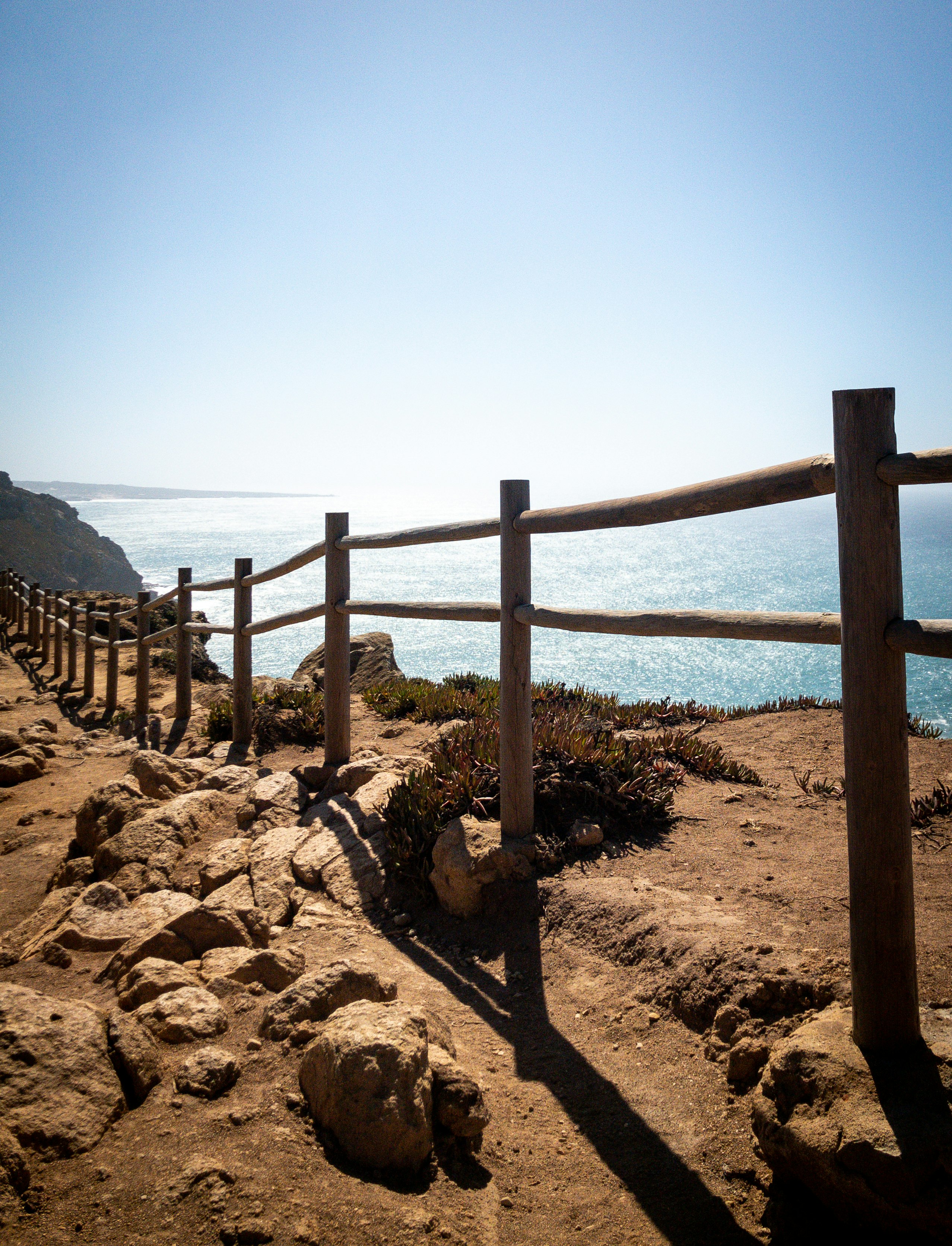 brown wooden fence on brown sand near body of water during daytime